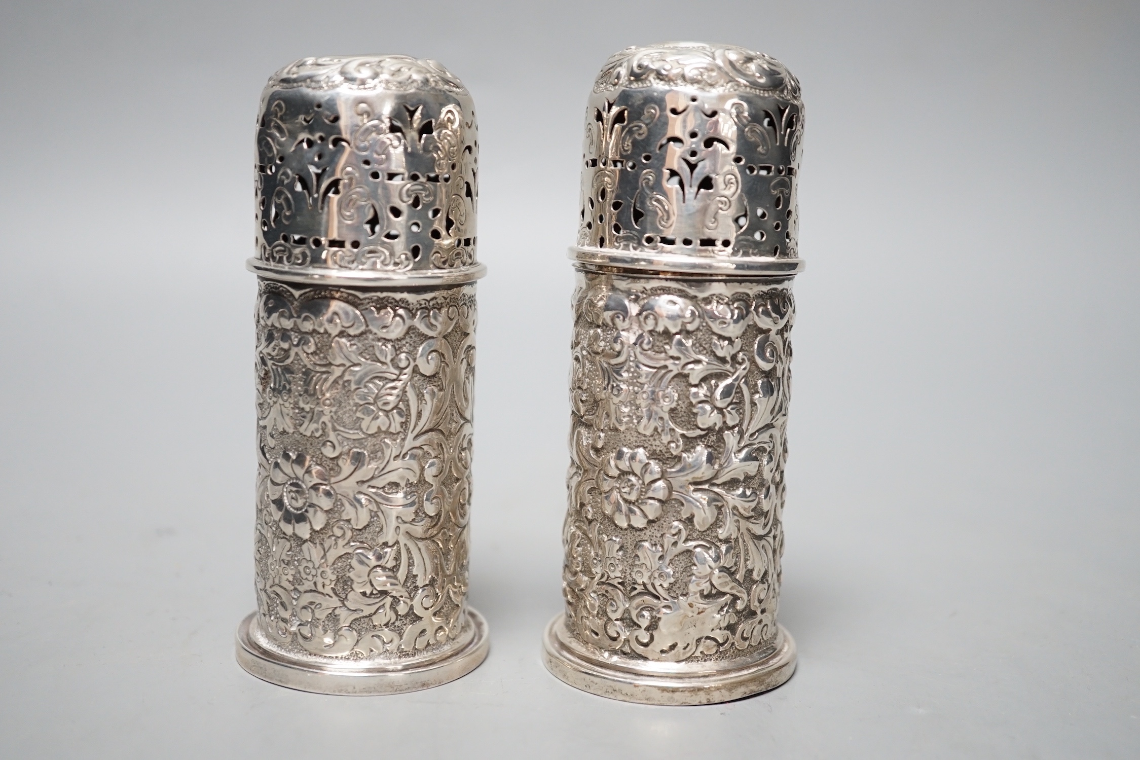 A pair of late Victorian embossed silver small lighthouse pepperettes, Horace Woodward & Co, London, 1895, 10.3cm, 156 grams.